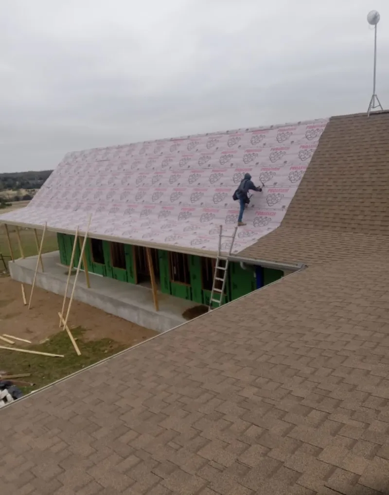 Worker preparing underlayment for a metal roof installation in Lawrence